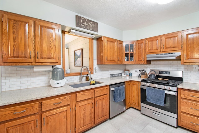 23127 Kendaville Rd, Pierson, MI 49339 - kitchen featuring stainless steel appliances, under cabinet range hood, a sink, brown cabinets, and decorative backsplash