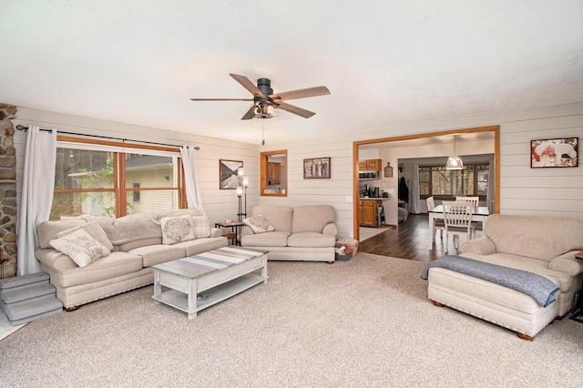 23127 Kendaville Rd, Pierson, MI 49339 - living area featuring wooden walls, ceiling fan, and carpet floors