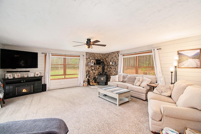 23127 Kendaville Rd, Pierson, MI 49339 - living area with a wood stove, plenty of natural light, a ceiling fan, and carpet floors