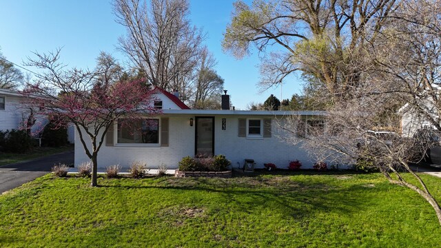 923 Maple St, Ludington, MI 49431 - view of front of property with brick siding, a chimney, and a front lawn