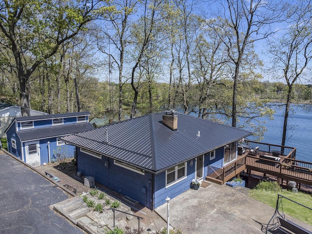 view of front of property featuring metal roof, a deck with water view, and a chimney
