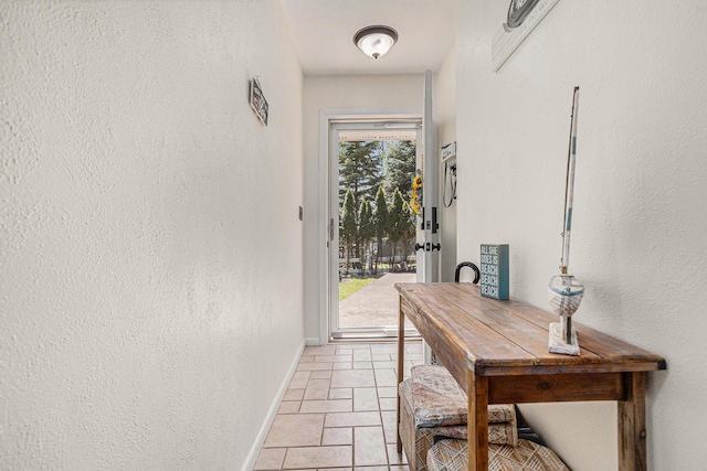 doorway to outside with baseboards and a textured wall