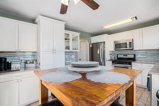 kitchen featuring stainless steel appliances, tasteful backsplash, white cabinetry, and ceiling fan