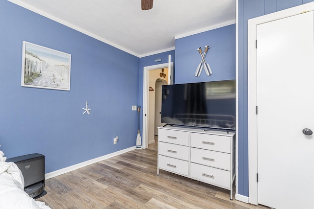 living area with wood finished floors, crown molding, baseboards, and ceiling fan