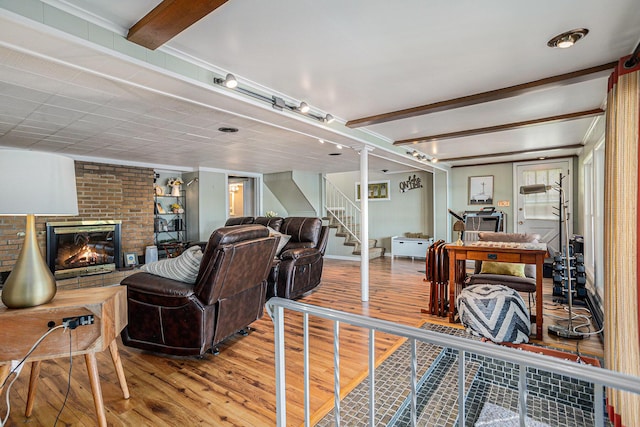 living room featuring wood finished floors, beamed ceiling, a fireplace, and stairway