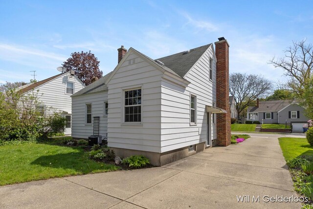 view of property exterior with a chimney, a yard, and central AC