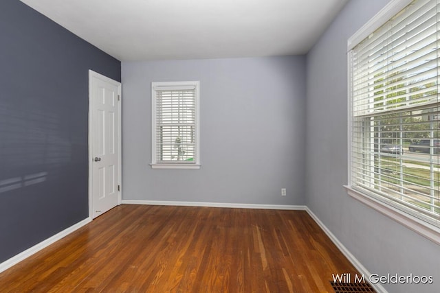 spare room with dark wood-style flooring and baseboards