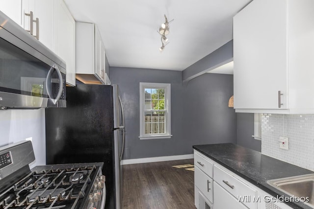kitchen featuring stainless steel appliances, tasteful backsplash, dark wood-style floors, white cabinetry, and dark stone counters