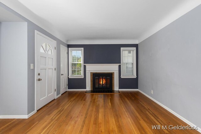 unfurnished living room with wood finished floors, a fireplace, and baseboards