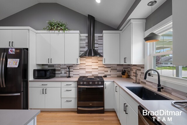 2151 Anderson Dr SE, Grand Rapids, MI 49506 - kitchen with black appliances, a sink, lofted ceiling, wall chimney range hood, and light countertops
