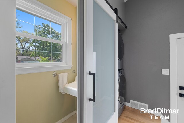 2151 Anderson Dr SE, Grand Rapids, MI 49506 - laundry area with stacked washer and clothes dryer, baseboards, a barn door, and wood finished floors