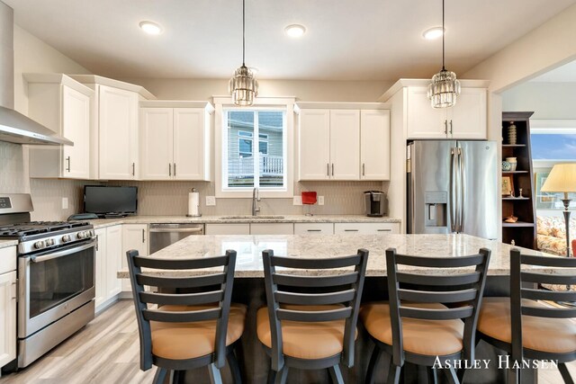 4700 Albright Ct SW Unit 6, Wyoming, MI 49418 - kitchen with stainless steel appliances, wall chimney exhaust hood, a sink, white cabinets, and a kitchen island