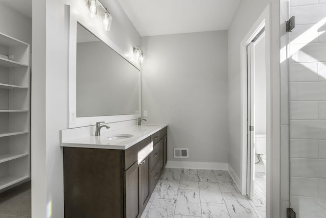 9423 Shoreway Dr, West Olive, MI 49460 - full bath with marble finish floors, baseboards, double vanity, toilet, and a walk in closet