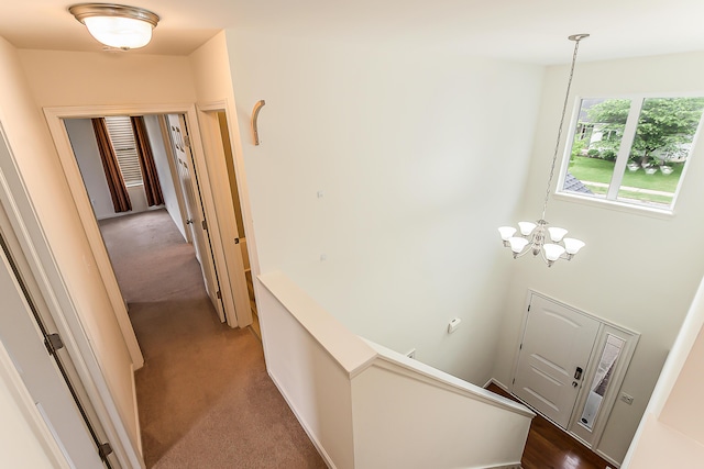 6837 Wellington Dr, Dexter, MI 48130 - hall with an upstairs landing, dark colored carpet, and a chandelier
