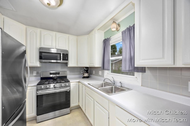 kitchen with appliances with stainless steel finishes, tasteful backsplash, a sink, and light countertops