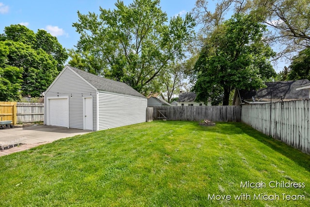 view of yard with a garage, an outdoor structure, driveway, and a patio area