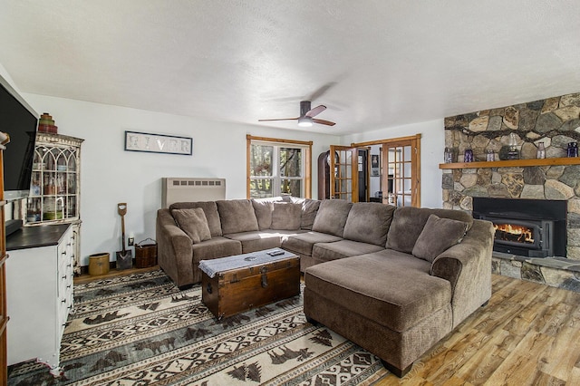 3897 N Chief Pontiac Trl, Branch, MI 49402 - living room with light wood-style flooring, ceiling fan, a stone fireplace, heating unit, and a textured ceiling