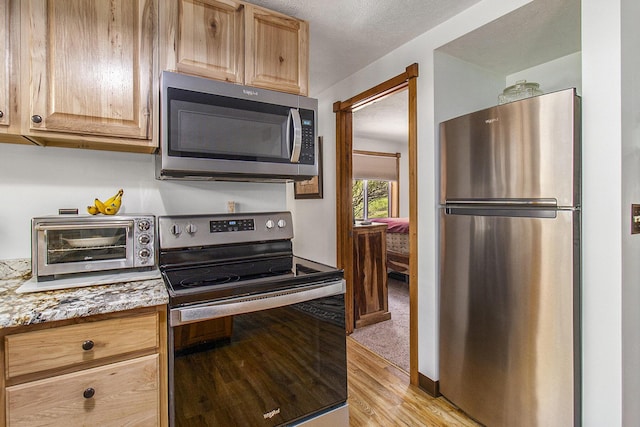 3897 N Chief Pontiac Trl, Branch, MI 49402 - kitchen featuring stainless steel appliances, light wood-style floors, light brown cabinets, and light stone countertops