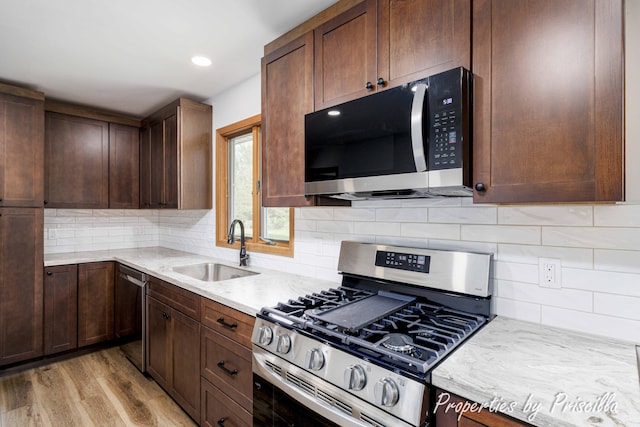 315 Hayes St NW, Comstock Park, MI 49321 - kitchen featuring stainless steel appliances, a sink, light wood finished floors, decorative backsplash, and light stone countertops