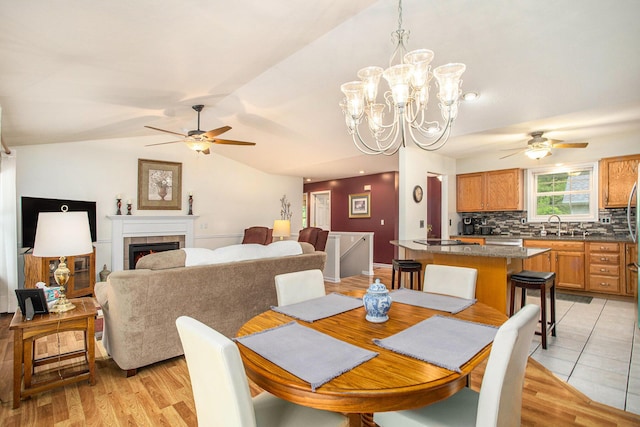 232 Embury Dr, Battle Creek, MI 49014 - dining room with a ceiling fan, vaulted ceiling, a tile fireplace, and a chandelier