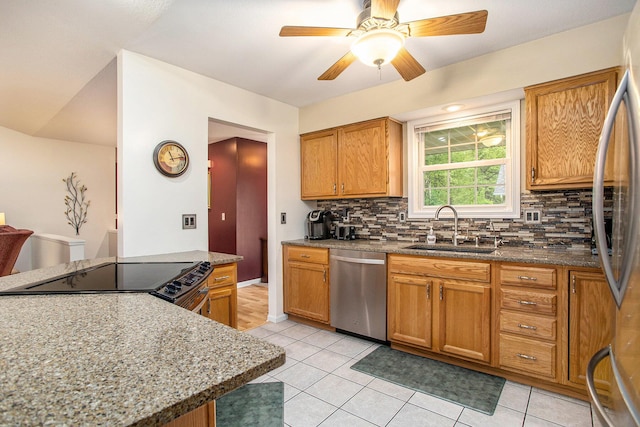 232 Embury Dr, Battle Creek, MI 49014 - kitchen featuring appliances with stainless steel finishes, a sink, tasteful backsplash, light tile patterned floors, and stone countertops
