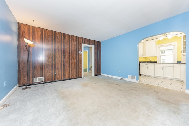 885 Hawthorne Ave, Ypsilanti, MI 48198 - unfurnished living room featuring arched walkways, light carpet, wood walls, and baseboards