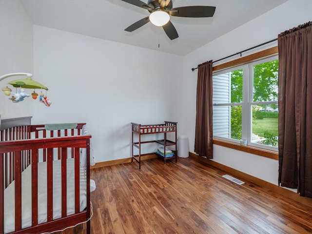 1518 M Dr S, East Leroy, MI 49051 - bedroom with wood finished floors, a crib, and a ceiling fan