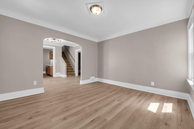 16568 Monica St, Detroit, MI 48221 - unfurnished room with arched walkways, light wood-style floors, baseboards, and stairway