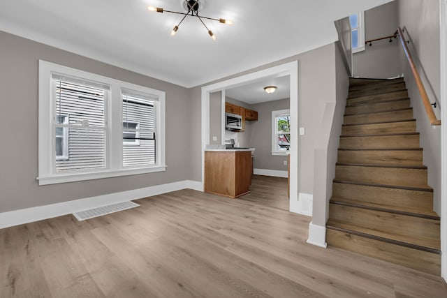 16568 Monica St, Detroit, MI 48221 - unfurnished living room featuring a chandelier, baseboards, light wood-style floors, and stairs