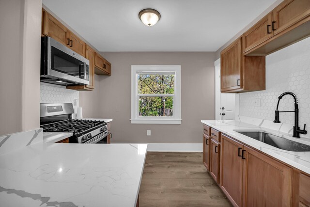 16568 Monica St, Detroit, MI 48221 - kitchen with appliances with stainless steel finishes, a sink, wood finished floors, light stone countertops, and tasteful backsplash
