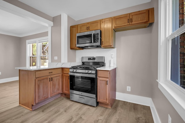 16568 Monica St, Detroit, MI 48221 - kitchen featuring appliances with stainless steel finishes, light wood finished floors, a peninsula, light countertops, and baseboards