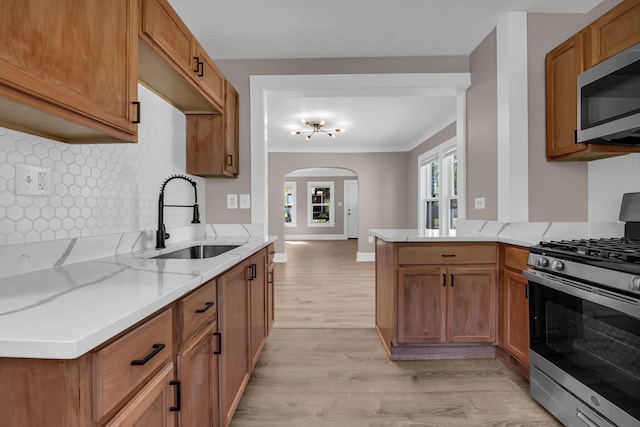 16568 Monica St, Detroit, MI 48221 - kitchen with appliances with stainless steel finishes, a sink, light wood-type flooring, tasteful backsplash, and arched walkways