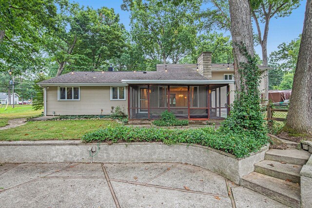 1514 Ferndale Blvd, Niles, MI 49120 - view of front of property with a sunroom, a chimney, a patio area, a front yard, and a shingled roof