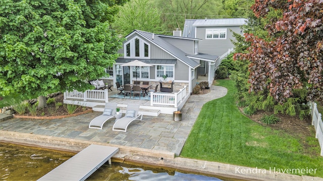 8779 Je Ne Be Dr NE, Rockford, MI 49341 - back of property with stone siding, outdoor dining space, a lawn, a patio, and a deck with water view