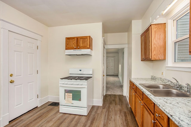 918 Kalamazoo Ave SE, Grand Rapids, MI 49507 - kitchen featuring white gas range oven, under cabinet range hood, a sink, dark wood-type flooring, and brown cabinetry