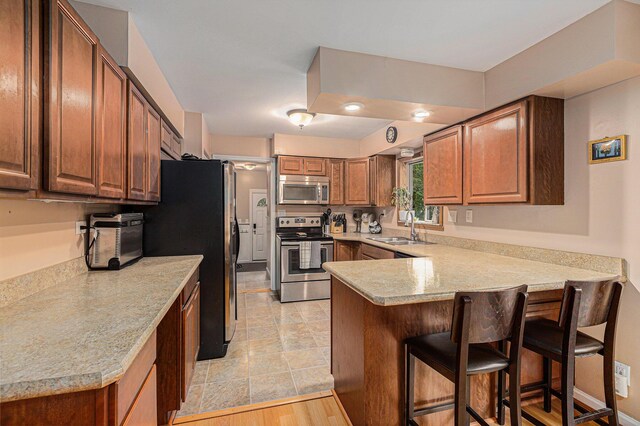 13195 Rainbow Dr, Gregory, MI 48137 - kitchen with appliances with stainless steel finishes, a peninsula, a sink, a kitchen breakfast bar, and light countertops