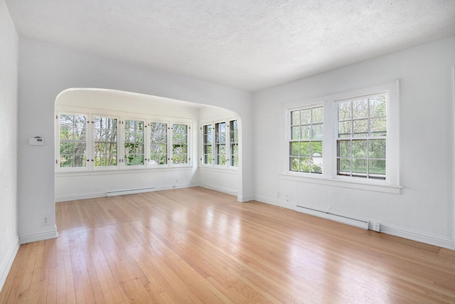 7566 Red Arrow Hwy, Stevensville, MI 49127 - spare room with wood-type flooring, baseboards, arched walkways, a baseboard radiator, and baseboard heating