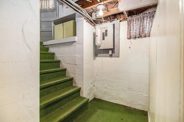 unfinished basement featuring electric panel and stairs