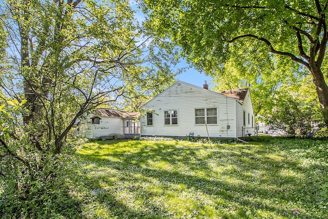 back of house with a lawn and a chimney