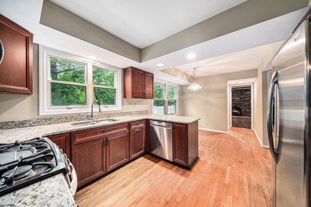 3630 Charter Pl, Ann Arbor, MI 48105 - kitchen featuring stainless steel appliances, a sink, light wood-style floors, a lit fireplace, and a peninsula