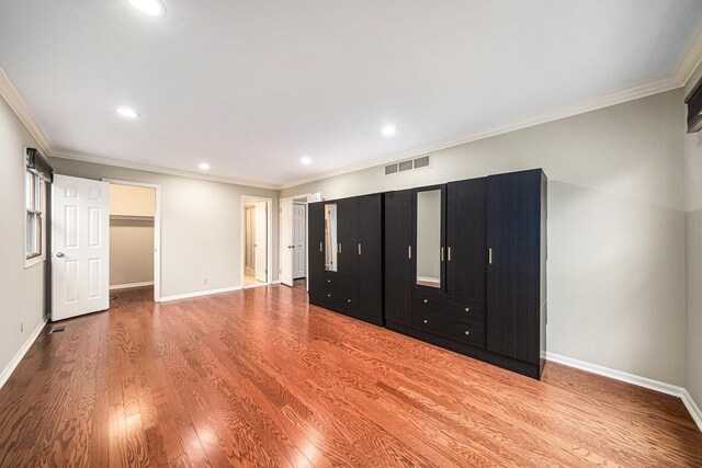 3630 Charter Pl, Ann Arbor, MI 48105 - unfurnished bedroom featuring wood finished floors, baseboards, ornamental molding, recessed lighting, and a walk in closet