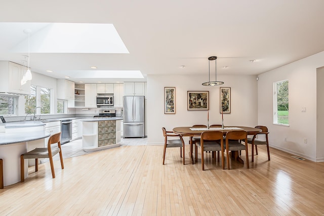 2277 W Huron River Dr, Ann Arbor, MI 48103 - dining space featuring light wood-style flooring, baseboards, a skylight, and recessed lighting