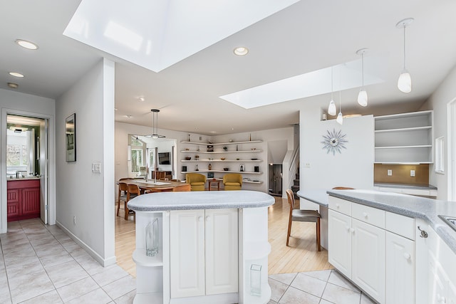 2277 W Huron River Dr, Ann Arbor, MI 48103 - kitchen with open shelves, a skylight, light countertops, light tile patterned flooring, and a center island