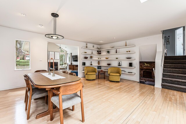 2277 W Huron River Dr, Ann Arbor, MI 48103 - dining area featuring light wood-style flooring, stairs, and a fireplace