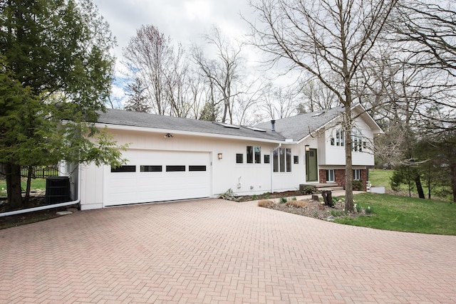 2277 W Huron River Dr, Ann Arbor, MI 48103 - view of front of property with a garage, decorative driveway, and central air condition unit