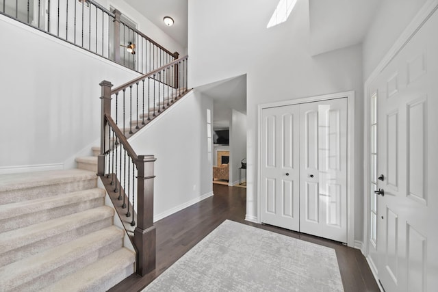 10478 River Edge Rd, Saline, MI 48176 - entrance foyer featuring stairs, a towering ceiling, dark wood-style floors, baseboards, and a fireplace