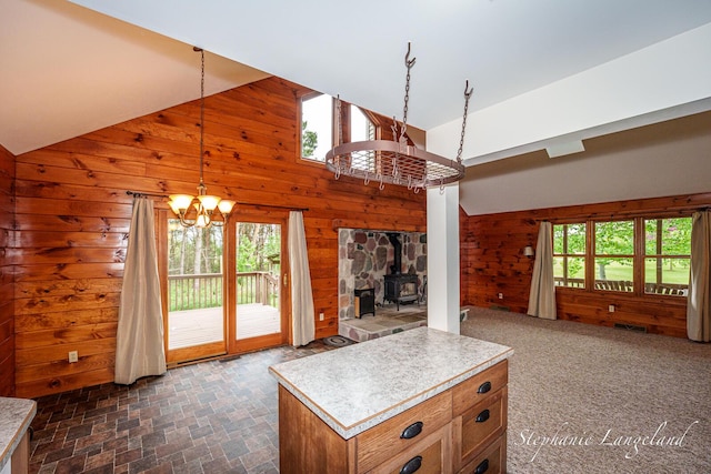 16913 Penny Ave NE, Sand Lake, MI 49343 - living area with wood walls, healthy amount of natural light, a chandelier, a wood stove, and high vaulted ceiling