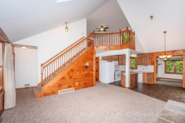 16913 Penny Ave NE, Sand Lake, MI 49343 - unfurnished living room with stairs, a chandelier, high vaulted ceiling, ceiling fan, and baseboards