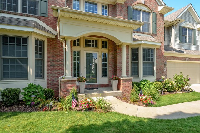7294 Mackenzie Ln, Portage, MI 49024 - view of exterior entry with brick siding, a garage, concrete driveway, and roof with shingles