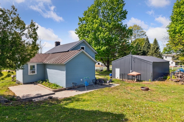 back of house featuring a lawn, a standing seam roof, metal roof, and a patio